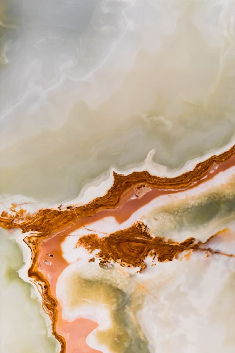 Close detail of warm onyx-marble slab with flowing amber and green veining